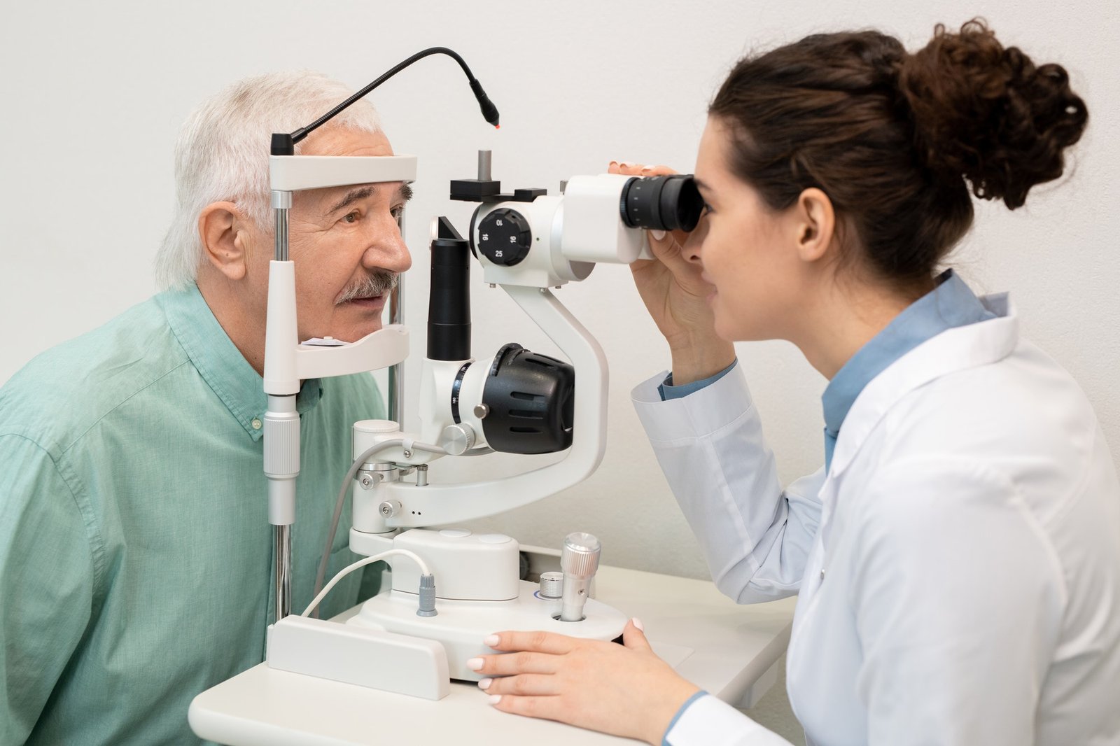 Young Brunette Female Ophthalmologist Testing Eyesight Of Senior Male Patient