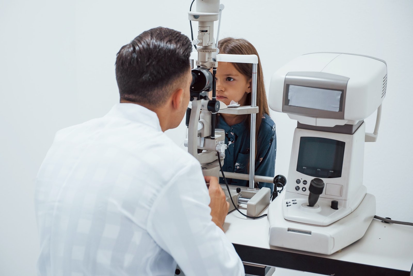 Young Ophthalmologist Is With Little Female Visitor In The Clinic